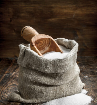 Salt in a wooden spoon. On wooden background.